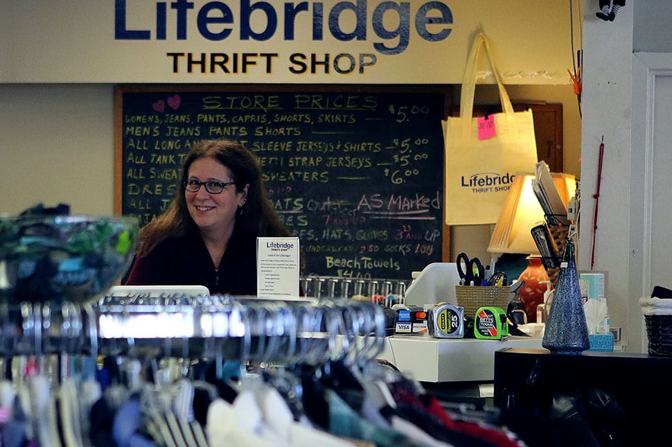A woman smiling behind the sales counter at Lifebridge Thrift Shop
