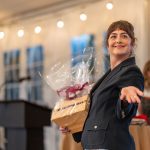 Director of Corporate & Community Partnerships Lindsay Barth presents a surprise raffle item at Breaking Bread, Building Hope paddle raising event