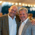 Al Tempkin and guest smile at a Fund-a-Need paddle raising event for Breaking Bread, Building Hope