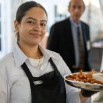 Photo of a Tedesco Country Club staff person serving coconut shrimp at Breaking Bread, Building Hope
