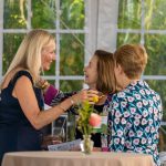 Three guests talk to each other beside a table at Breaking Bread, Building Hope
