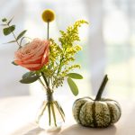 A photo of a flower bouquet and pumpkin decorating the Breaking Bread, Building Hope event