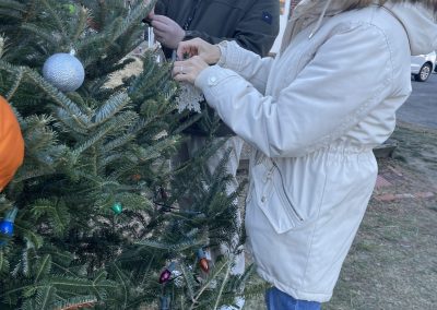 Two people tying ornaments to the Christmas tree