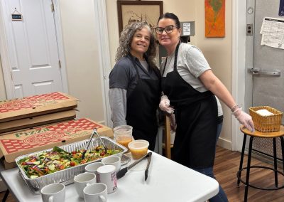 Two happy volunteers serving pizza and salad