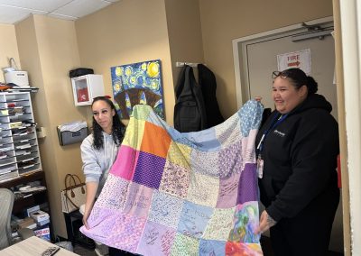 Two women holding up handmade quilt