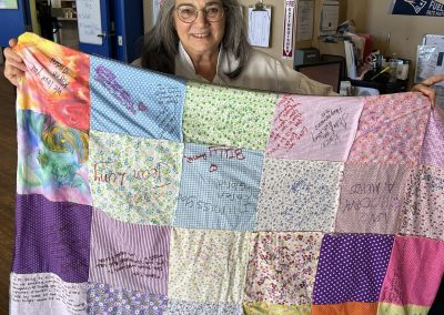A woman holding up a handmade quilt