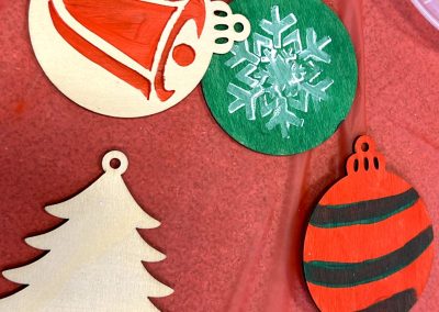 Hand painted ornaments, one with a snowflake, one with a bell, and one with stripes